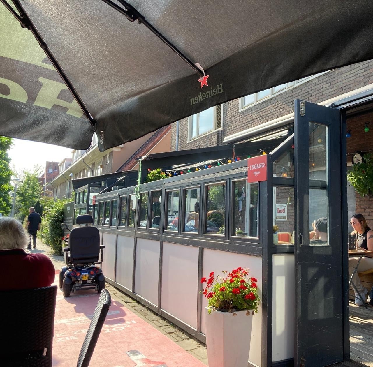 Het overdekte terras met parasols en geraniums