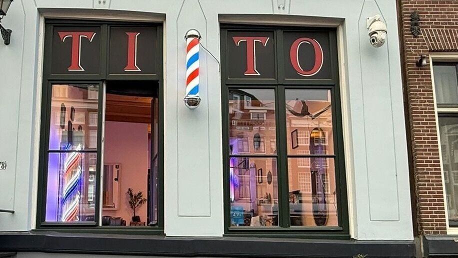 De gevel van Tito Barbershop met barberpaal